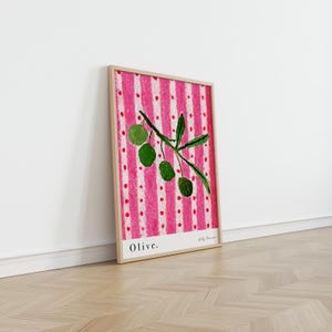 Puede incluir: Una impresi&oacute;n enmarcada de una rama de olivo verde con fondo a rayas rosa y blanco. La impresi&oacute;n tiene la palabra "Olive." en la parte inferior y el nombre del artista "Holly Francesca" en una fuente m&aacute;s peque&ntilde;a.