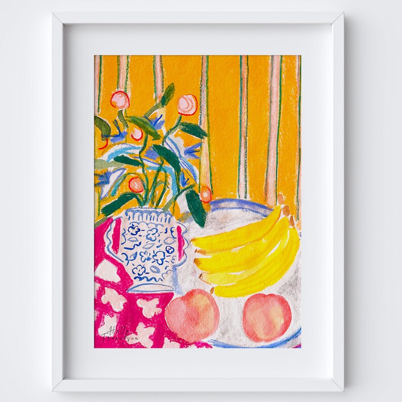 Op de afbeelding: Een stilleven met een blauwe en witte keramische vaas met een boeket roze bloemen en groene bladeren. De vaas staat op een roze en witte tafelkleed met een bord gele bananen en roze perziken.