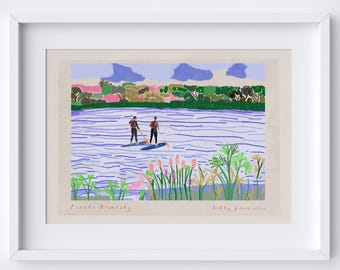 Könnte beinhalten: Ein gerahmter Kunstdruck, der zwei Personen beim Stand-Up-Paddling auf einem blauen See zeigt. Das Kunstwerk zeigt eine farbenfrohe Landschaft mit grünen Bäumen, rosa Gebäuden und einem hellblauen Himmel mit Wolken. Die Wörter "Paddle Boarding" und "Kelly Annisito" sind geschrieben.