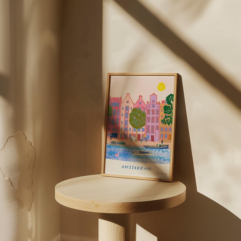 K&ouml;nnte beinhalten: Eine farbenfrohe Illustration von Amsterdam, Niederlande, mit einem Farbschema in Rosa, Gelb und Blau. Die Illustration zeigt einen Kanal mit Booten und Geb&auml;uden am Rande. Der Text "AMSTERDAM" befindet sich am unteren Rand der Illustration.