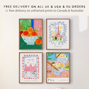 May include: Four framed art prints with colorful illustrations. One depicts oranges in a bowl, another shows the Eiffel Tower in Japan, a third features Angkor Wat in Cambodia, and the last displays a bowl of Pho.