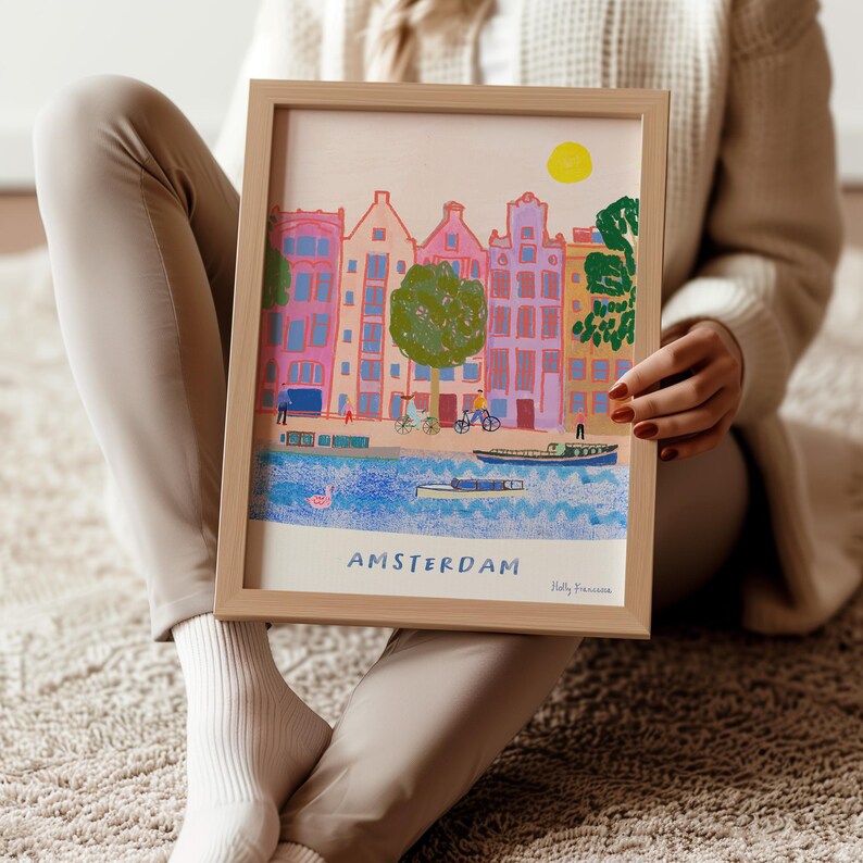 K&ouml;nnte beinhalten: Eine gerahmte Illustration von bunten Geb&auml;uden mit einem Kanal davor. Die Illustration tr&auml;gt den Titel "AMSTERDAM" und ist signiert mit "Holly Francesca".