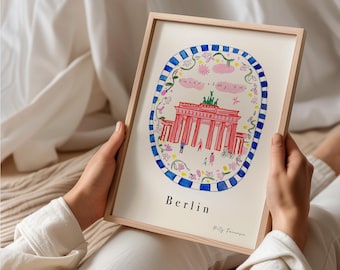 Può includere: Una stampa artistica incorniciata con un'illustrazione ad acquerello della Porta di Brandeburgo a Berlino. L'opera è racchiusa in un bordo ovale a strisce blu e bianche con accenti floreali, il testo Berlin e una firma in basso.