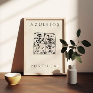 May include: A framed print with the word "AZULEJOS" at the top and "PORTUGAL" at the bottom. The print features a black and white illustration of four square tiles with different designs, including a bird, a rabbit, and flowers.