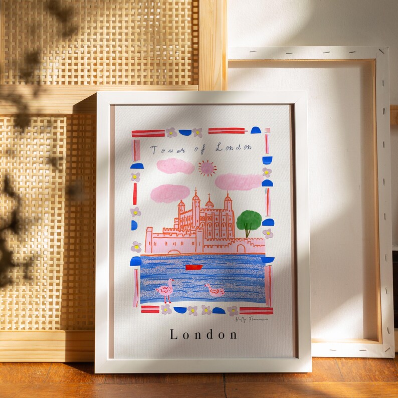 Puede incluir: Una impresi&oacute;n enmarcada en blanco con una ilustraci&oacute;n colorida de la Torre de Londres. La ilustraci&oacute;n est&aacute; rodeada por un borde de formas geom&eacute;tricas rojas, azules y blancas. El texto "Tower of London" y "London" est&aacute; impreso en negro.