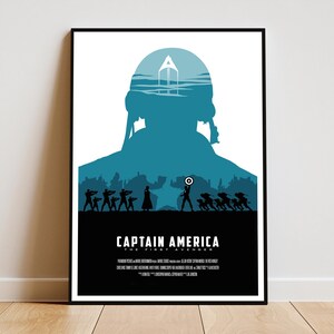May include: A framed poster featuring a teal silhouette of Captain America with his shield, set against a cityscape and a white background. The title "CAPTAIN AMERICA THE FIRST AVENGER" is displayed in white text at the bottom.