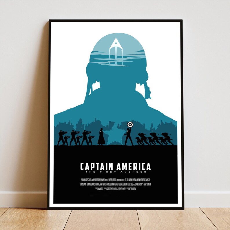 May include: A framed poster featuring a teal silhouette of Captain America with his shield, set against a cityscape and a white background. The title "CAPTAIN AMERICA THE FIRST AVENGER" is displayed in white text at the bottom.