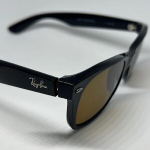 Puede incluir: Gafas de sol negras con montura gruesa y lentes tintadas en marr&oacute;n. La patilla presenta el logotipo plateado de Ray-Ban en relieve en el lateral. El dise&ntilde;o incluye una forma rectangular cl&aacute;sica con un detalle de bisagra met&aacute;lica.