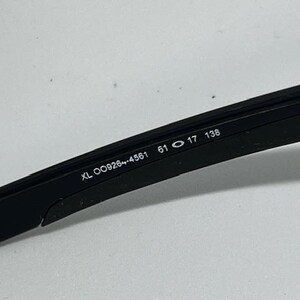 May include: A black sunglass temple arm featuring white printed text on the inner side. The text reads XL OO9264-4561 61 17 138, indicating the model number and specific frame measurements in millimeters for this eyewear component.