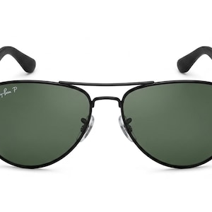 May include: Aviator sunglasses featuring a thin black metal frame and dark green lenses. The left lens displays the white Ray-Ban P logo. The design includes a double bridge, adjustable nose pads, and black temple arms with curved tips.
