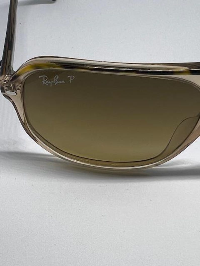 May include: Sunglasses with a translucent light brown frame featuring a tortoiseshell pattern along the top rim. The brown tinted lenses include the white Ray-Ban P logo printed in the upper corner, indicating polarised lens technology.