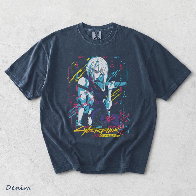 May include: A dark blue short-sleeve t-shirt featuring a graphic print of the character Lucy from Cyberpunk Edgerunners. The design includes the text "LUCY" repeated in a digital font, alongside yellow, pink, and blue abstract geometric lines.