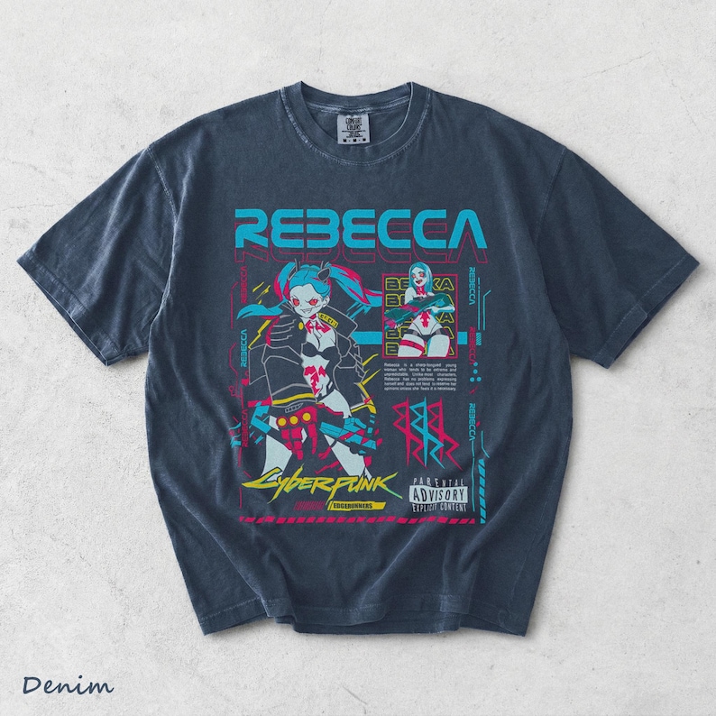 K&ouml;nnte beinhalten: Ein dunkelblaues Kurzarm-T-Shirt mit einem Grafikdruck der Figur Rebecca aus Cyberpunk Edgerunners. Das Design enth&auml;lt den Namen REBECCA in gro&szlig;en cyanfarbenen Buchstaben, ein Parental Advisory-Label und verschiedene technische Textelemente.