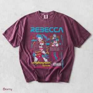 K&ouml;nnte beinhalten: Ein beerenfarbenes Kurzarm-T-Shirt mit einem Grafikdruck der Figur Rebecca aus Cyberpunk Edgerunners. Das Design enth&auml;lt den Text REBECCA, CYBERPUNK, EDGERUNNERS sowie ein wei&szlig;es Parental Advisory Explicit Content-Etikett.