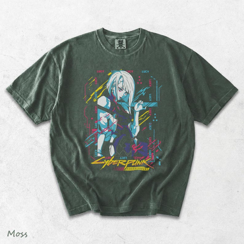 May include: A dark moss green short-sleeve t-shirt featuring a graphic print of a character with white hair. The design includes neon blue, pink, and yellow accents with the text "LUCY" repeated and "CYBERPUNK EDGERUNNERS" printed at the bottom.