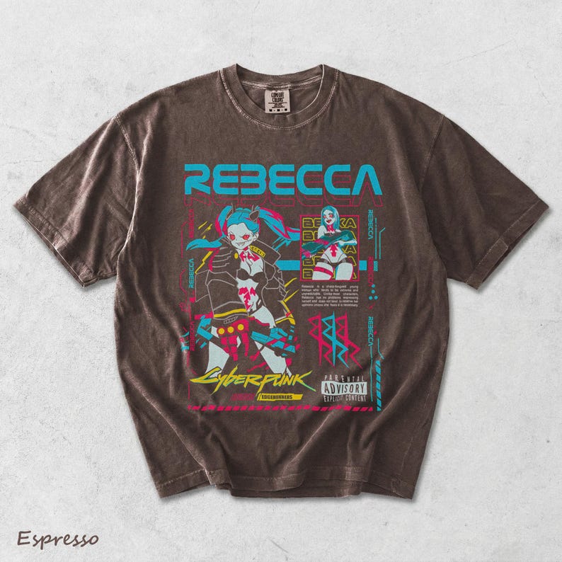 K&ouml;nnte beinhalten: Ein espressofarbenes Kurzarm-T-Shirt mit einem Grafikdruck der Figur Rebecca aus Cyberpunk Edgerunners. Das Design enth&auml;lt leuchtend blaue und rosa Akzente, den Schriftzug REBECCA sowie ein Parental Advisory Explicit Content-Etikett.