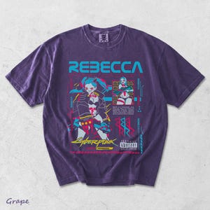 K&ouml;nnte beinhalten: Ein traubenfarbenes T-Shirt mit einem Grafikdruck der Figur Rebecca aus Cyberpunk Edgerunners. Das Design enth&auml;lt den Namen REBECCA in gro&szlig;en cyanfarbenen Buchstaben, ein Parental Advisory Explicit Content-Label und verschiedene neonfarbene Akzente.