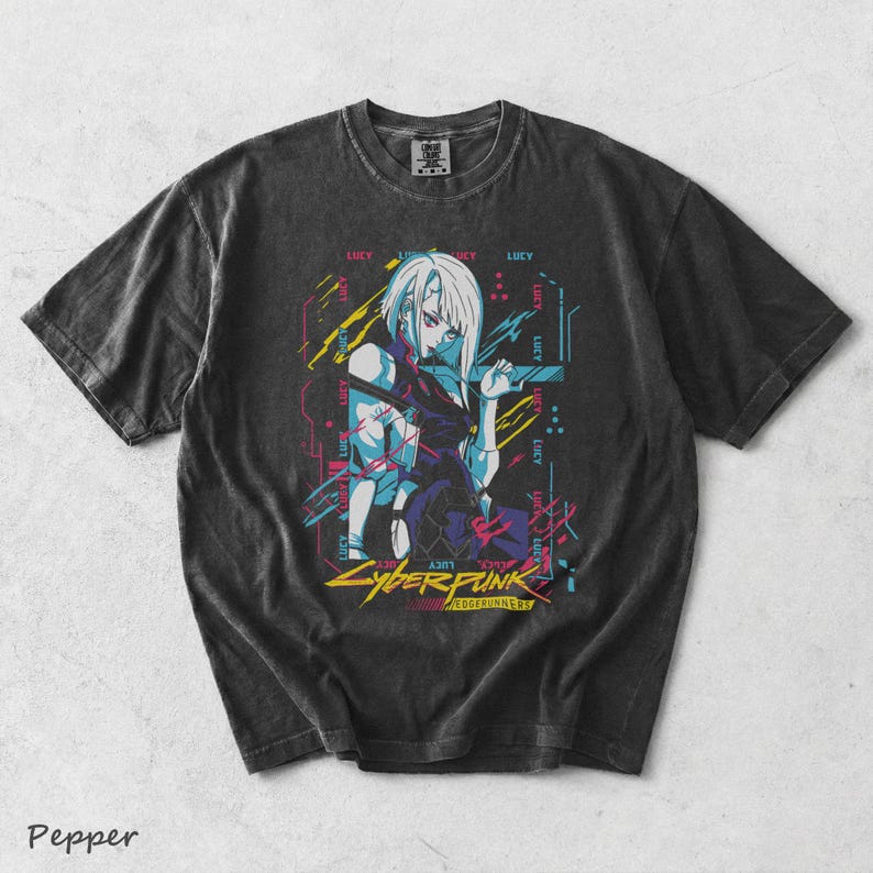 May include: A charcoal grey short-sleeve t-shirt featuring a graphic print of the character Lucy from Cyberpunk Edgerunners. The design includes neon blue, pink, and yellow accents with the text Cyberpunk Edgerunners and the name Lucy repeated.