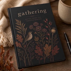 May include: A black hardback journal with the text gathering NOTES FROM THE TURNING SEASON in gold lettering. The cover features a detailed illustration of a small bird perched among autumn leaves, wildflowers, and seed pods in copper tones.