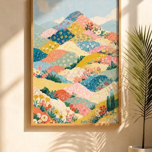 May include: A framed art print depicting a colorful landscape of rolling hills. The artwork features a patchwork of floral patterns in shades of pink, yellow, blue, and green. The sky is a light blue with hints of clouds. The frame is a light brown color.