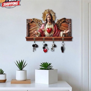 May include: A wooden key holder featuring a religious figure with outstretched arms, a red heart, and a golden halo. The key holder has four hooks with keys hanging from them. The words "FREE SHIPPING" are in the upper left corner.