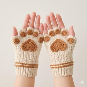 May include: A pair of fingerless gloves crocheted from cream-colored yarn, featuring a brown paw pad design on the palm area. Each glove includes four small circular brown pads at the finger openings and a large heart-shaped brown pad.