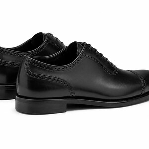 Men’s black leather cap toe Oxford shoes with classic lace-up construction, polished finish and refined formal dress shoe silhouette.