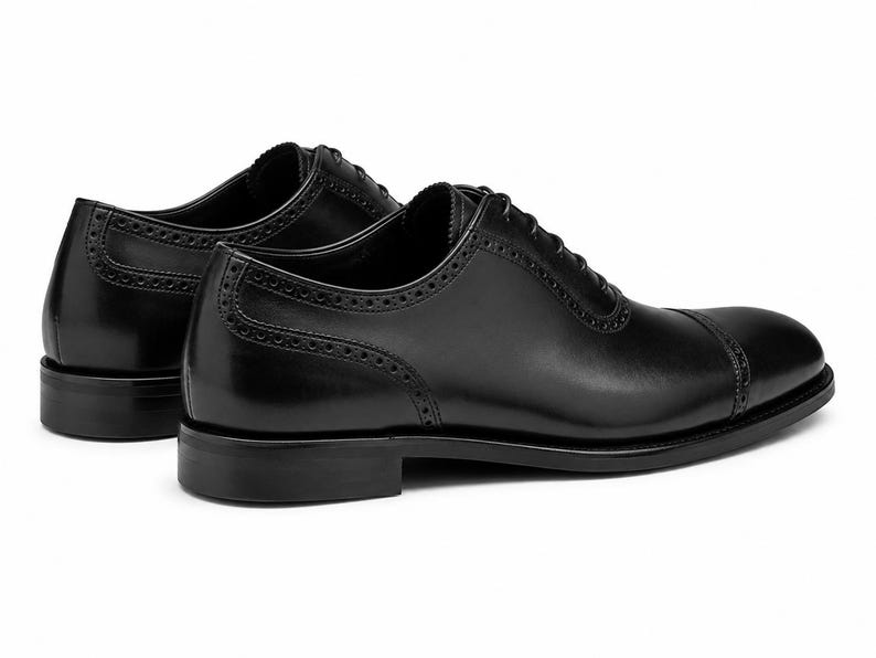 Men’s black leather cap toe Oxford shoes with classic lace-up construction, polished finish and refined formal dress shoe silhouette.