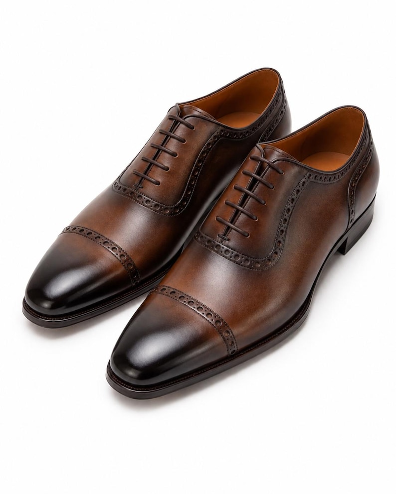Handmade brown leather Oxford dress shoes with cap toe, closed lacing and elegant low heel.