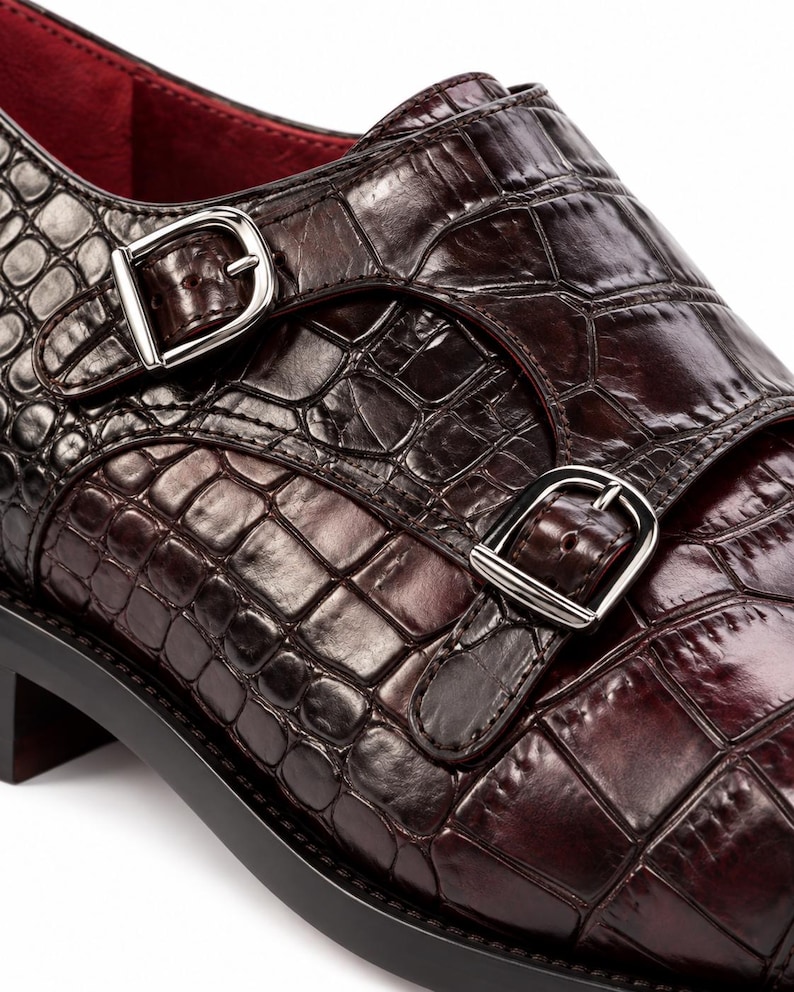 Close-up of croc embossed dark chocolate brown leather monk strap shoe with two polished silver buckles and detailed handcrafted stitching.