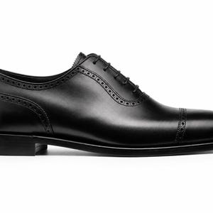 Black leather Oxford dress shoes for men featuring cap toe design, clean stitching, lace-up closure and elegant formal profile.