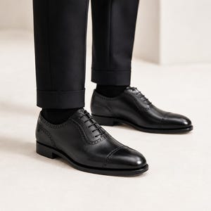 Model wearing men’s black cap toe Oxford shoes with tailored trousers for weddings, business meetings, office wear and formal events.