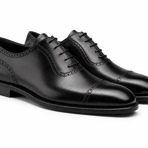 Men’s black leather cap toe Oxford shoes with classic lace-up construction, polished finish and refined formal dress shoe silhouette.