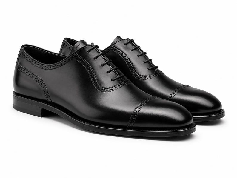 Men’s black leather cap toe Oxford shoes with classic lace-up construction, polished finish and refined formal dress shoe silhouette.