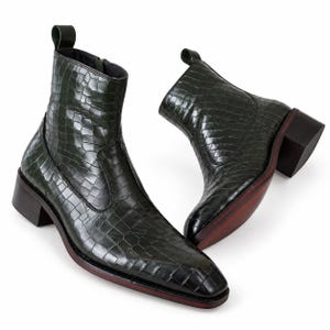 Peut inclure: Une paire de bottines vert foncé avec une texture gaufrée façon crocodile brillante, un bout carré, une languette à l'arrière et un talon bloc empilé avec une bordure de semelle brun rougeâtre. Les bottines ont une fermeture éclair latérale.
