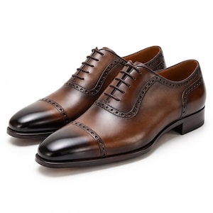 Men’s burnished brown leather cap toe Oxford shoes with subtle brogue perforations and polished formal dress shoe finish.