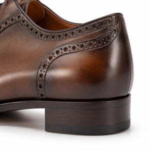 Close-up of rich brown patina leather, hand-burnished shading and detailed stitching on handmade men’s dress shoes.