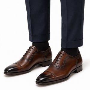 Man wearing brown leather cap toe Oxford shoes with tailored trousers for wedding, business, office and formal styling.