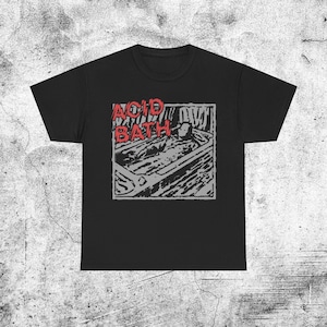 Può includere: T-shirt nera con un design grafico. Il design presenta le parole "ACID BATH" in rosso, sopra un'illustrazione in scala di grigi di una persona in una vasca da bagno. Il design è racchiuso in un telaio rettangolare.