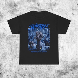 Puede incluir: Camiseta negra con el nombre de la banda "Suffocation" en azul, sobre un gráfico azul y blanco de una criatura y el texto "Breeding the Spawn". La camiseta está hecha de un material suave.