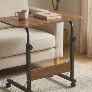 May include: A mobile side table with a rectangular walnut-toned wooden top and a black metal frame. The table features adjustable height settings secured by two star-shaped knobs on the vertical supports and four small wheels at the base.