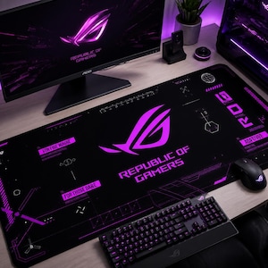 Può includere: Un tappetino per mouse da gioco nero con la scritta "REPUBLIC OF GAMERS" e un logo viola. Sono visibili anche un monitor del computer, una tastiera e un mouse. L'installazione è su una scrivania di legno. La tastiera e il mouse hanno la retroilluminazione viola.