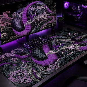 Peut inclure: Un grand tapis de bureau rectangulaire présentant une illustration détaillée d'un dragon violet et noir avec des accents de crinière blanche, entouré de motifs de nuages stylisés. Le tapis est placé sous un clavier et une souris noirs.