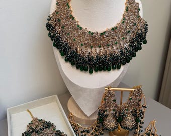 Conjunto de joyas nupciales artificiales con intrincados detalles en oro antiguo, una piedra brillante y perlas de un intenso color verde esmeralda.
