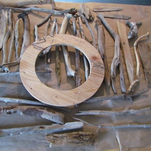 May include: A collection of driftwood pieces of various sizes and shapes, arranged on a brown surface. A wooden circle with a hole in the center is also included.