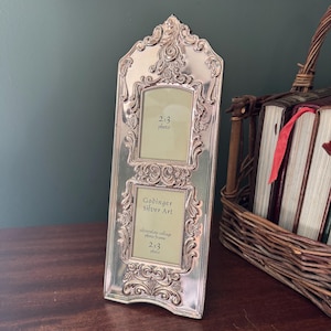 May include: A silver-plated vertical collage photo frame with an ornate, embossed scrollwork border. The frame holds two 2x3 inch photos and features the text Godinger Silver Art, silverplate collage photo frame, 2x3 photo on the bottom insert.