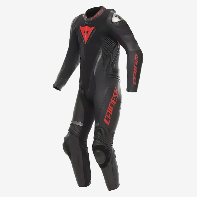 Puede incluir: Traje de carreras de motociclismo negro con detalles en rojo. El traje muestra la marca "DAINESE" en rojo en los brazos y las piernas, y un logotipo rojo en el pecho. Tiene protecciones en rodillas y hombros.