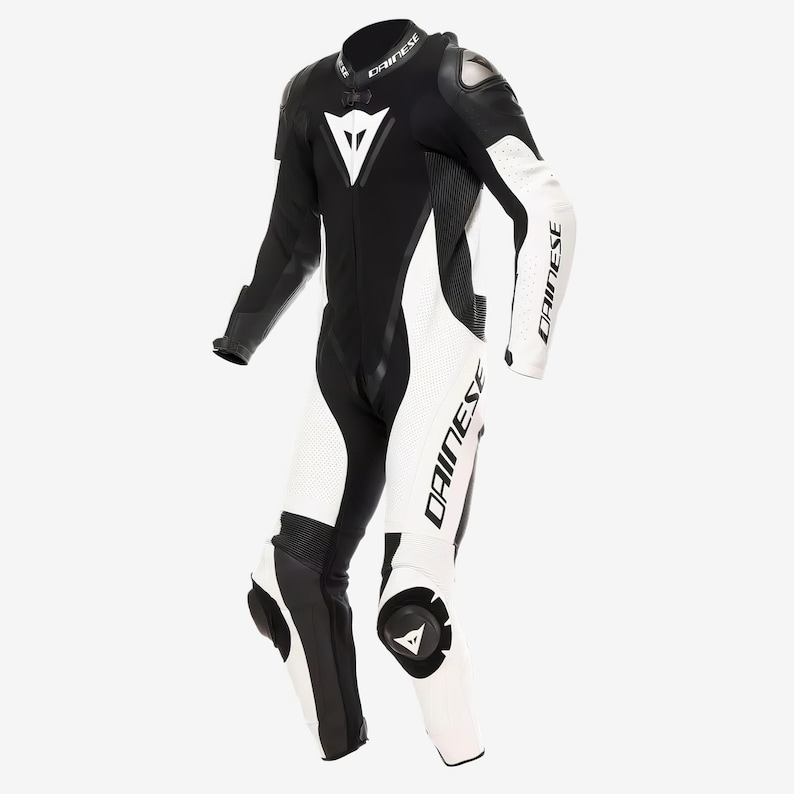以下が含まれることがあります： 袖と脚にブランド名「DAINESE」がプリントされた、白と黒のオートバイレース用スーツ。肩と膝には保護パッドが付いた流線型のデザイン。胸と膝には白い三角形のロゴがあります。