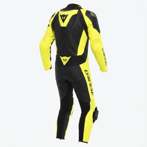 May include: A black and yellow motorcycle racing suit with the Dainese logo. The suit features yellow panels on the arms, legs, and sides, and black panels on the back, shoulders, and inner legs. Protective padding is visible on the knees and elbows.