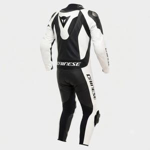 以下が含まれることがあります： 胸と脚に「DAINESE」のブランド名がプリントされた、白と黒のオートバイレーススーツ。腕、肩、脚には白いパネル、胴体と脚の内側には黒いパネルが付いています。肩と膝には保護パッドが付いています。